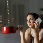 Frustrated woman claiming insurance for water leaks sitting on a couch in the living room at home